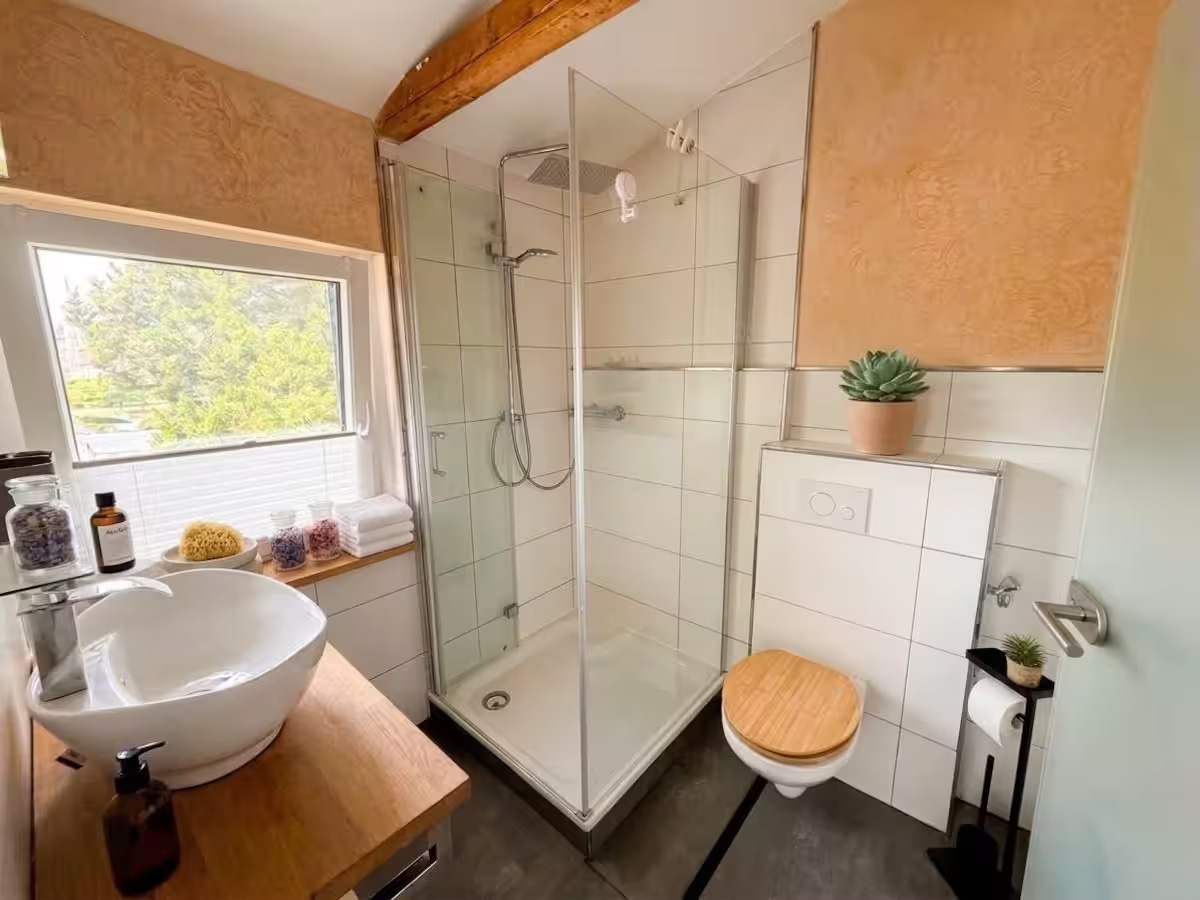 Badezimmer mit Dusche, Waschtisch und Fenster
