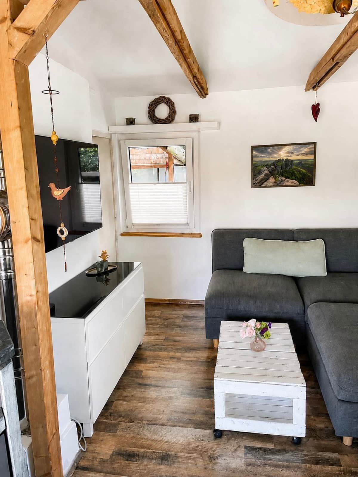 Wohnzimmer mit Sofa, Fernseher und sichtbaren Holzbalken